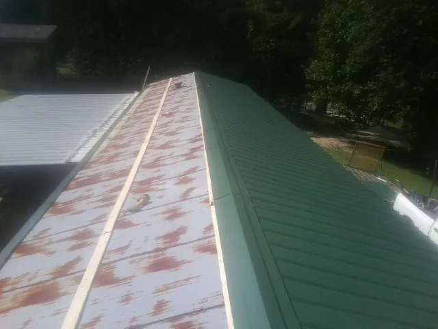 Old rusted panels beside newly installed green metal roofing — Wind Damage Roof Repair by Roofing Brothers in Avilla