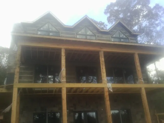 Dormers and porch framing on a large log home under construction — Roof Coating work by our crew in Avilla