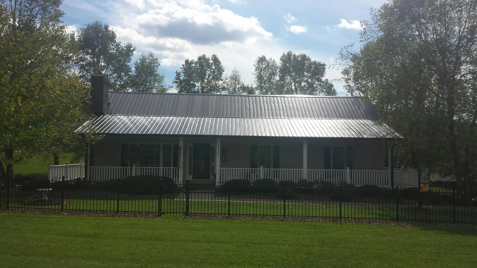 Gray metal roof on a brick ranch with a full width front porch — Gutter Guard Installation work by our crew in Avilla