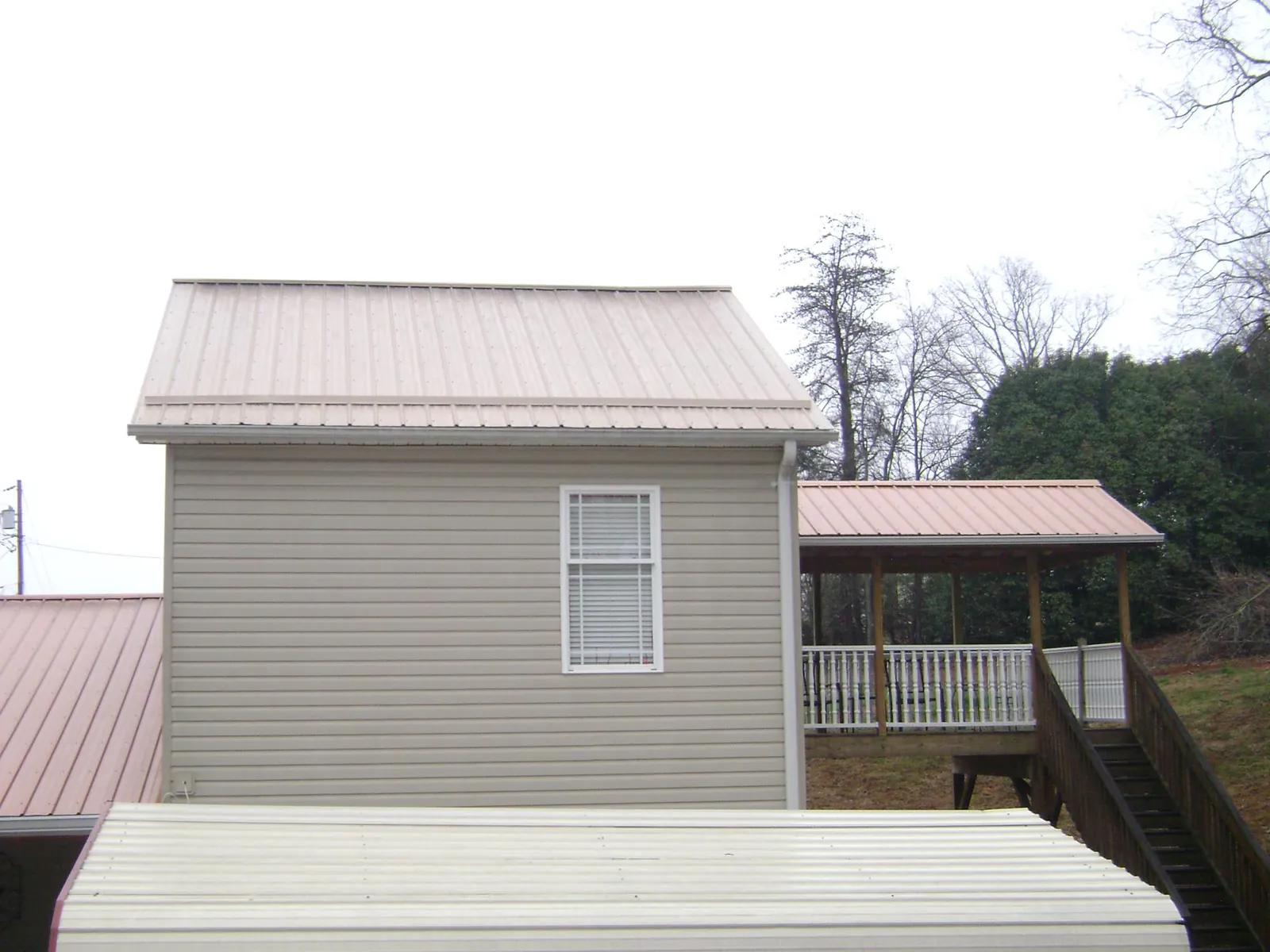 Tan metal roofs on a two story addition and attached porch, from a Roof Replacement job in Avilla