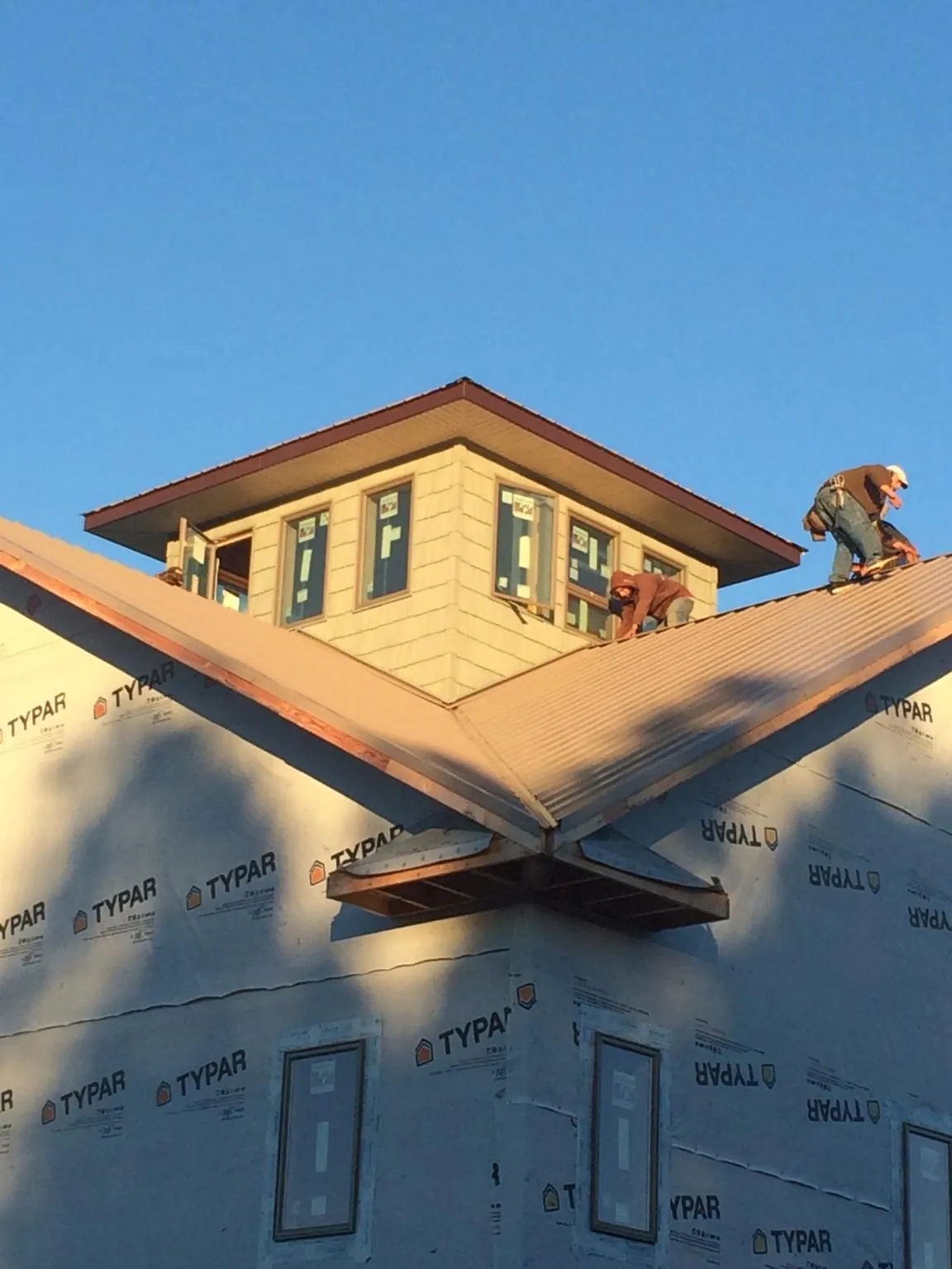 Roofers working around a rooftop cupola on a new metal roof at sunset — Roof Waterproofing in Avilla by Roofing Brothers
